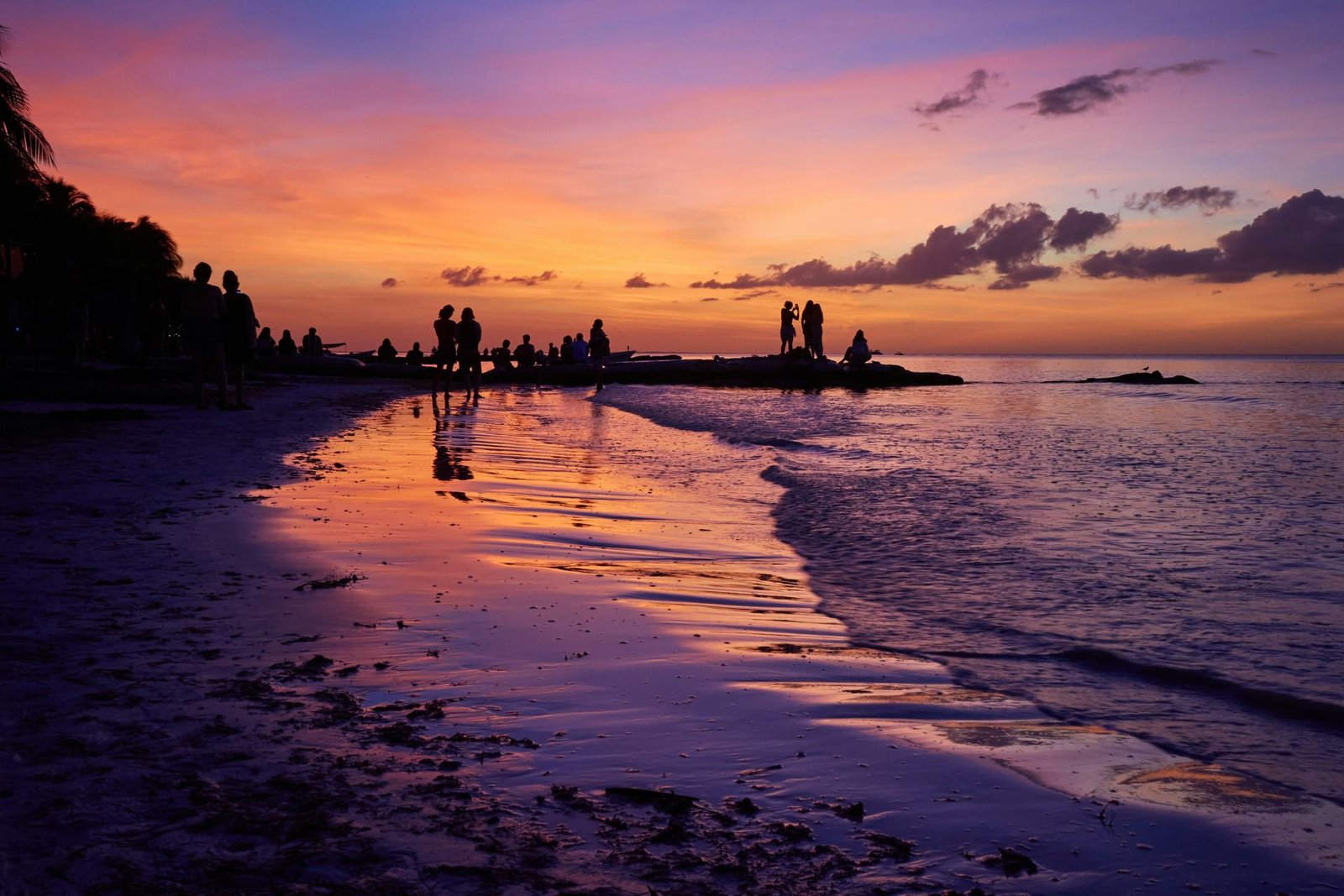 Atardecer sobre una playa de México con siluetas de viajeros